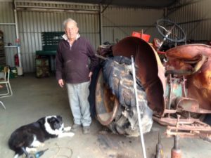 volunteer standing next to 1950 International AW6 tractor before it was restored